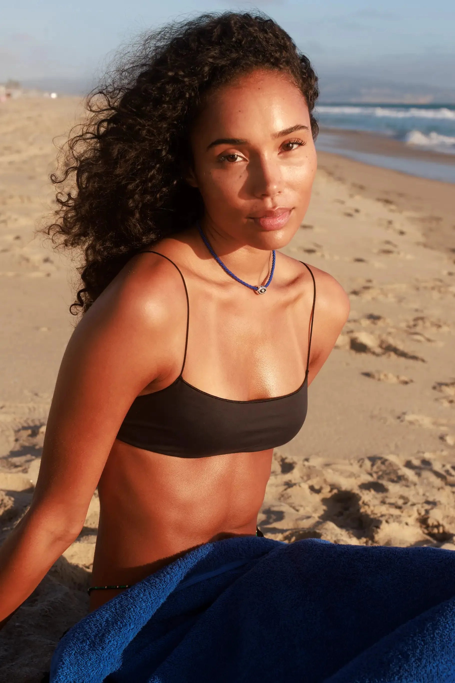 Model wearing MyAleph Luna Cord Necklace in a summer beach look, cobalt blue cord necklace with silver evil eye pendant