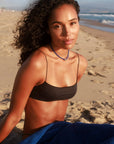 Model wearing MyAleph Luna Cord Necklace in a summer beach look, cobalt blue cord necklace with silver evil eye pendant