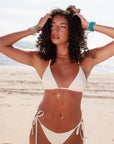Model wearing MyAleph Luna Cord Necklace in a summer beach look, red cord evil eye necklace with gold pendant