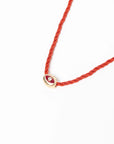 MyAleph Luna Cord Necklace with red silk cord, gold evil eye pendant, and white background