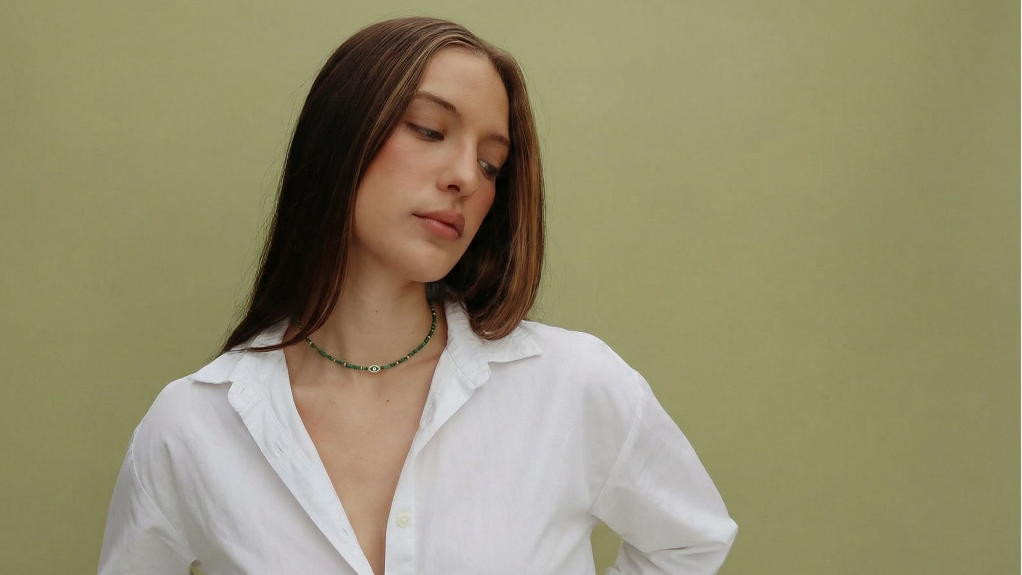 Model wearing the Juliana malachite necklace with green beads and evil eye detail, styled with a white button-down shirt