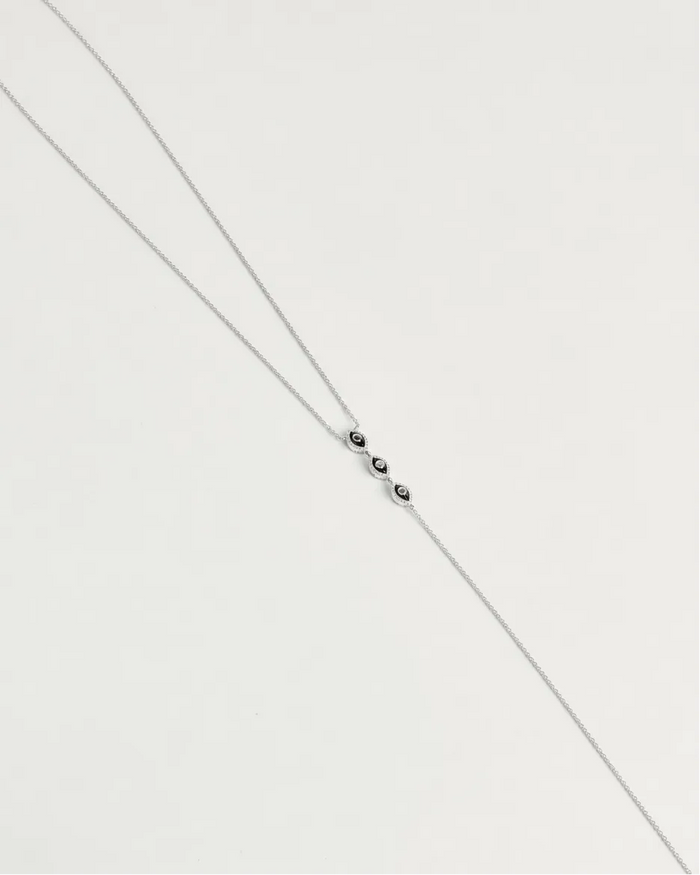 Mayra Evil Eye Body Chain in silver dipped laid flat on white surface with three black enamel evil eye charms at center