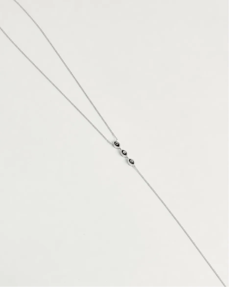 Mayra Evil Eye Body Chain in silver dipped laid flat on white surface with three black enamel evil eye charms at center