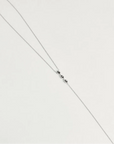 Mayra Evil Eye Body Chain in silver dipped laid flat on white surface with three black enamel evil eye charms at center