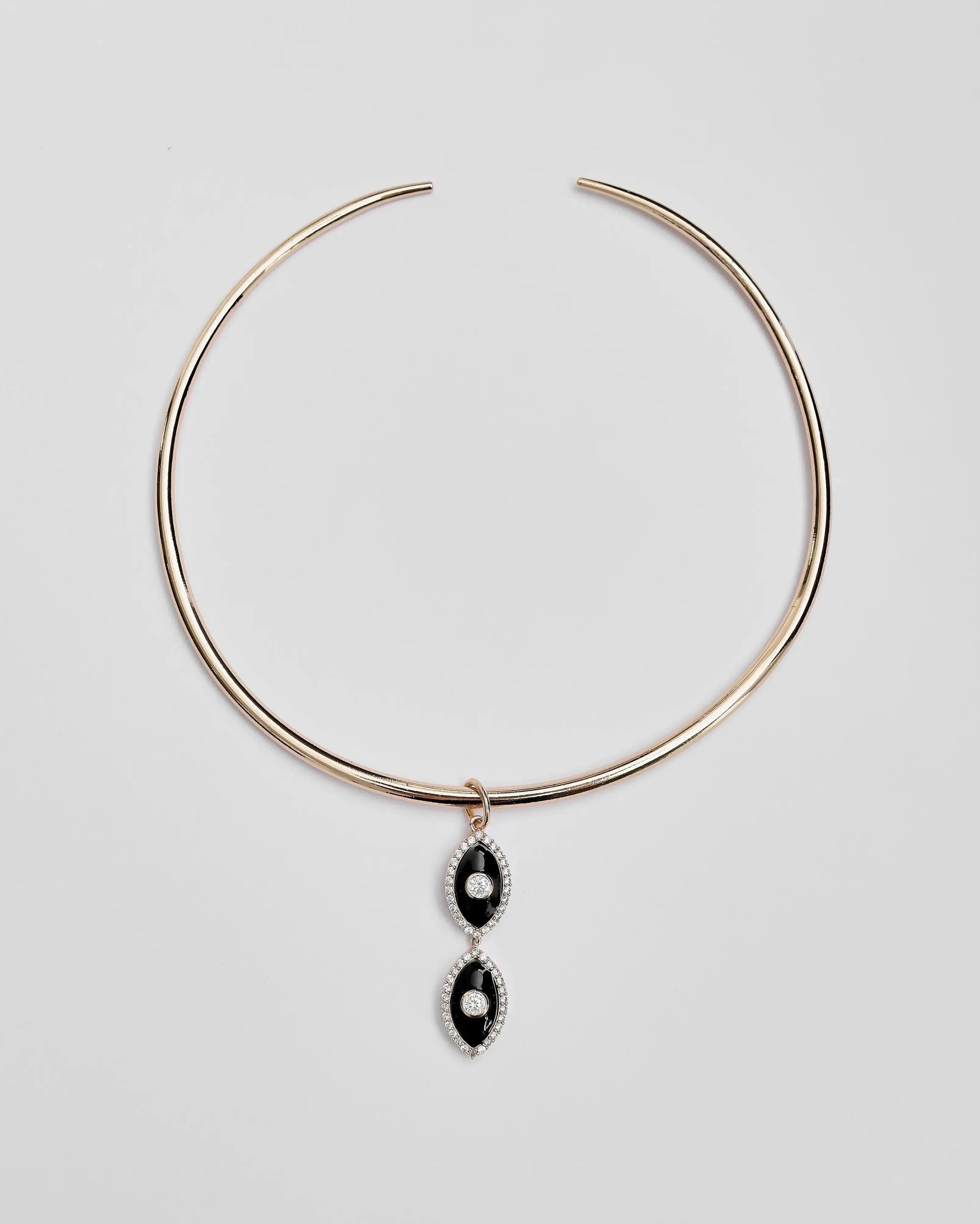 Gold collar necklace with two black enamel evil eye charms displayed flat against a white background.