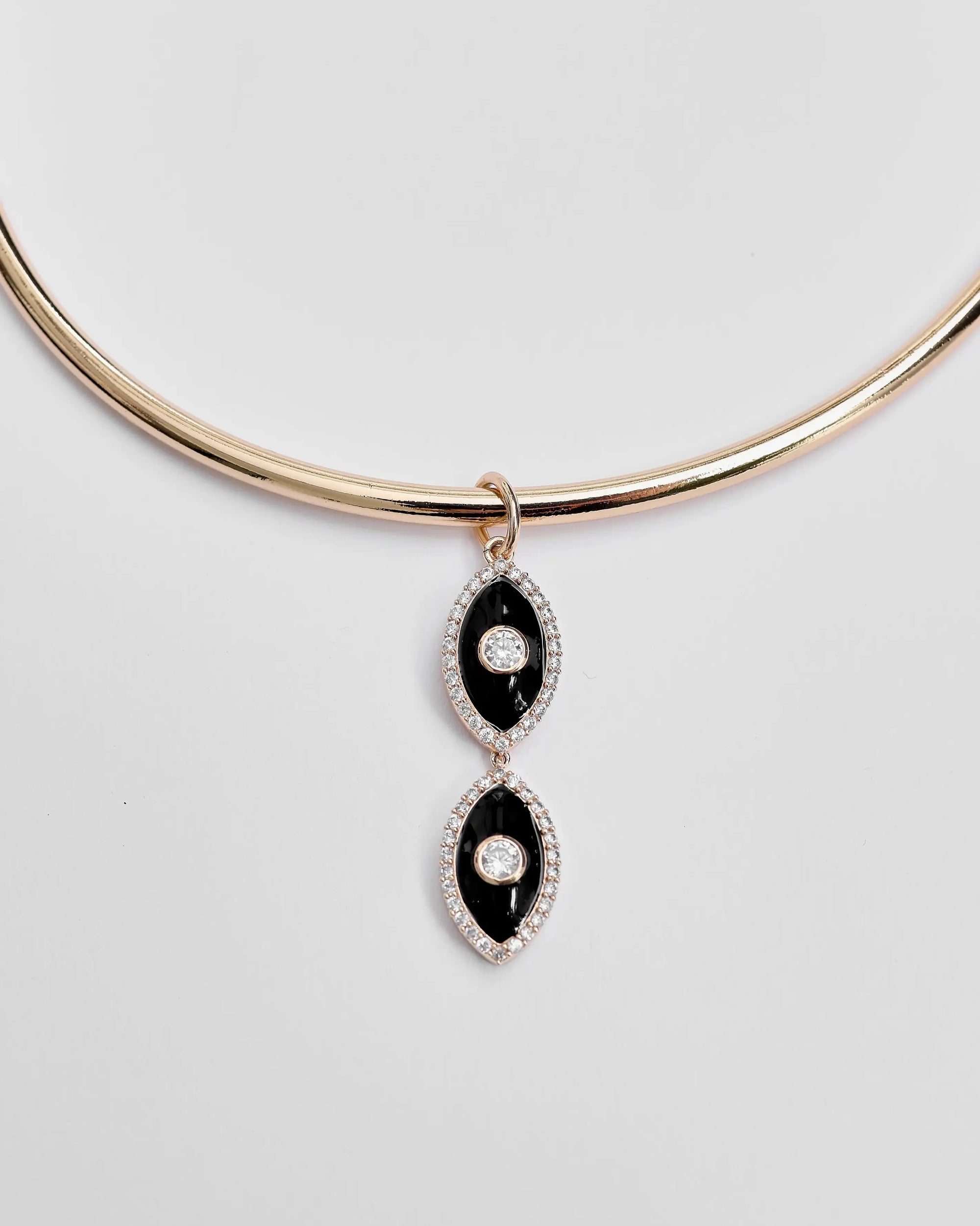 Close-up of the necklace laid flat, highlighting the dual black enamel evil eye charms.

