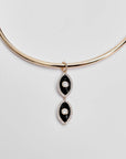 Close-up of the necklace laid flat, highlighting the dual black enamel evil eye charms.

