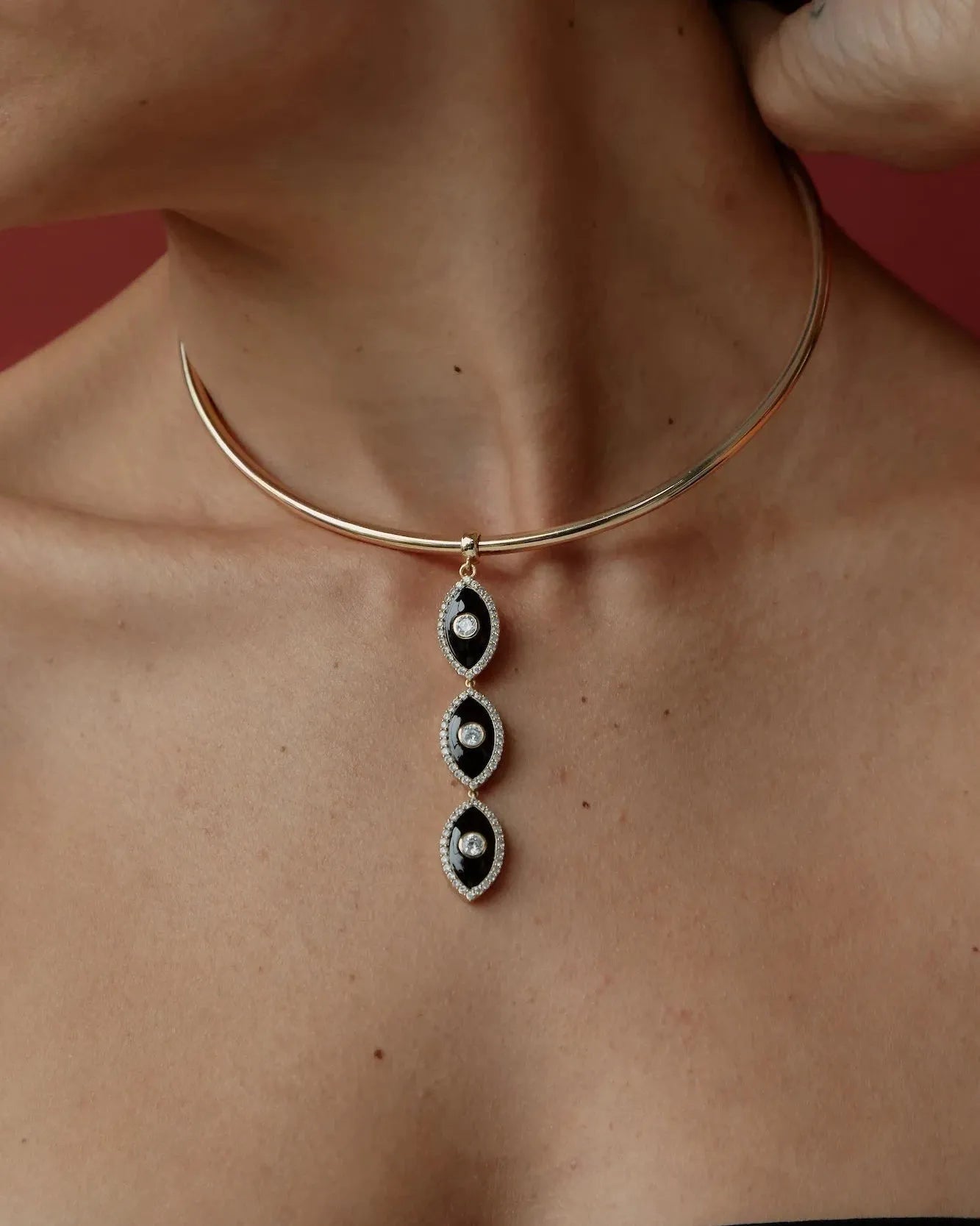 Mayra Evil Eye Choker with black and white pendants on a person's neck against a red background