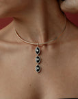 Mayra Evil Eye Choker with black and white pendants on a person's neck against a red background