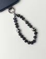 Mini Aura phone charm with smoky quartz beads and premium dipped silver evil eye talismans attached to black phone case on white background.