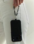 Model holding black phone with Mini Aura smoky quartz phone charm featuring silver dipped evil eye details.