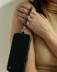 Mini Aura smoky quartz phone charm styled against neutral outfit with premium dipped silver accents.