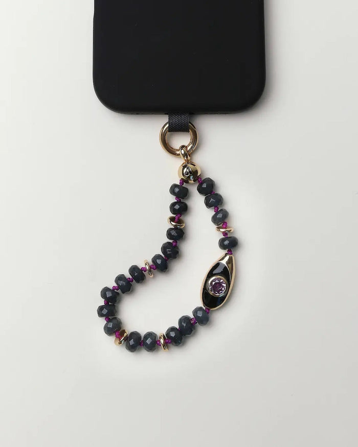 Mini Aya phone charm with smoky quartz gemstone beads, gold accents, evil eye charm, and amethyst CZ stone attached to a black phone case.
