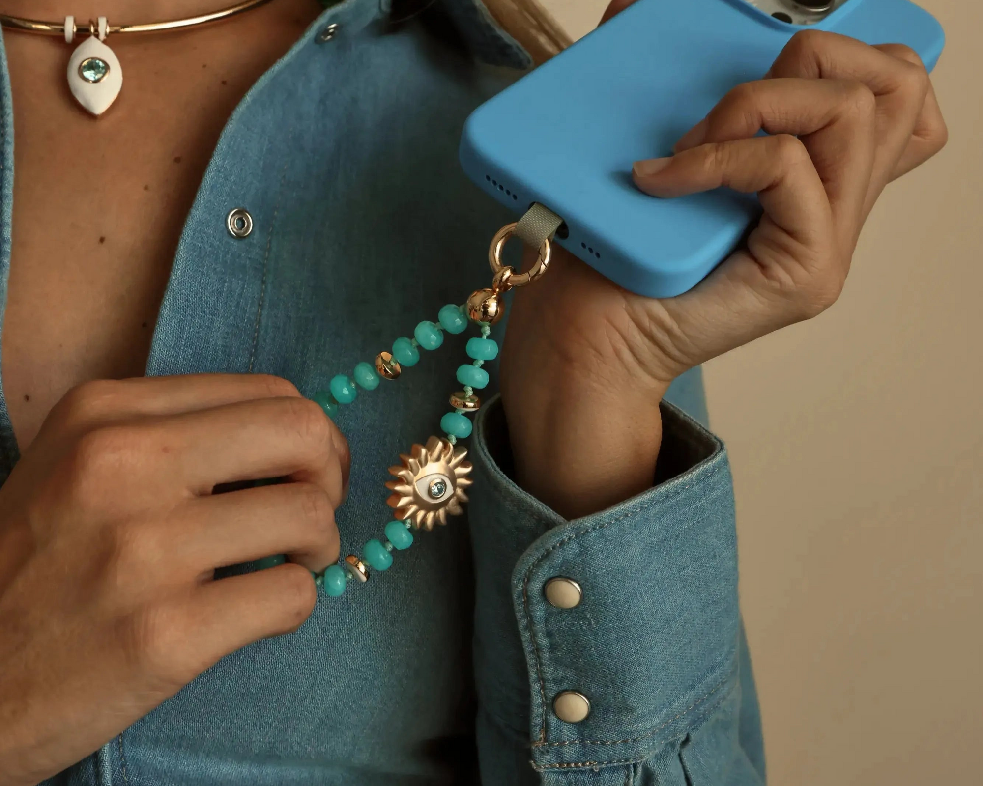 Mini India phone charm in aqua quartz with blue gemstone beads and gold plated hardware attached to a phone.