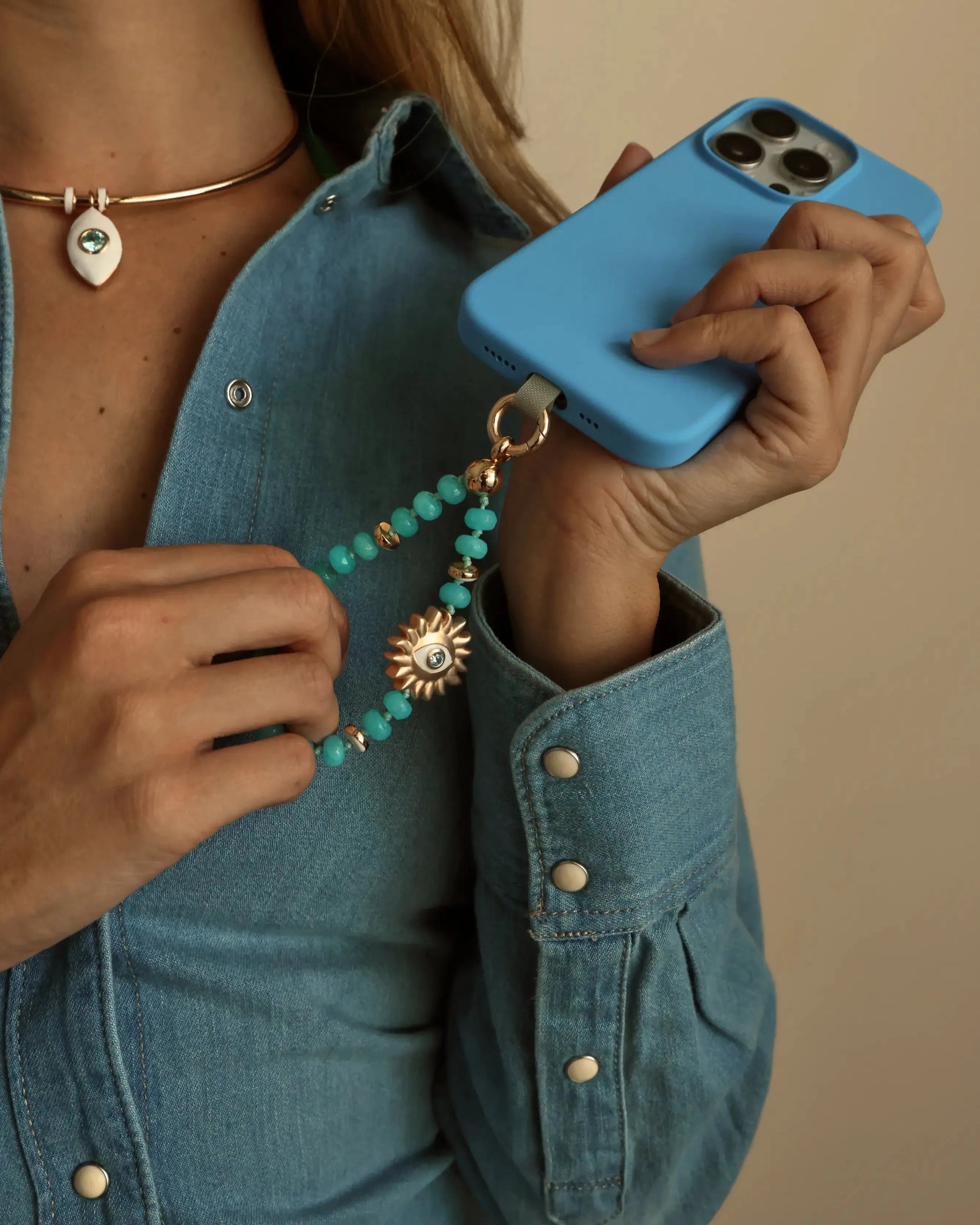 Lifestyle shot of model in denim holding Aqua Quartz Mini India Phone Charm on phone