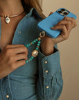 Lifestyle shot of model in denim holding Aqua Quartz Mini India Phone Charm on phone