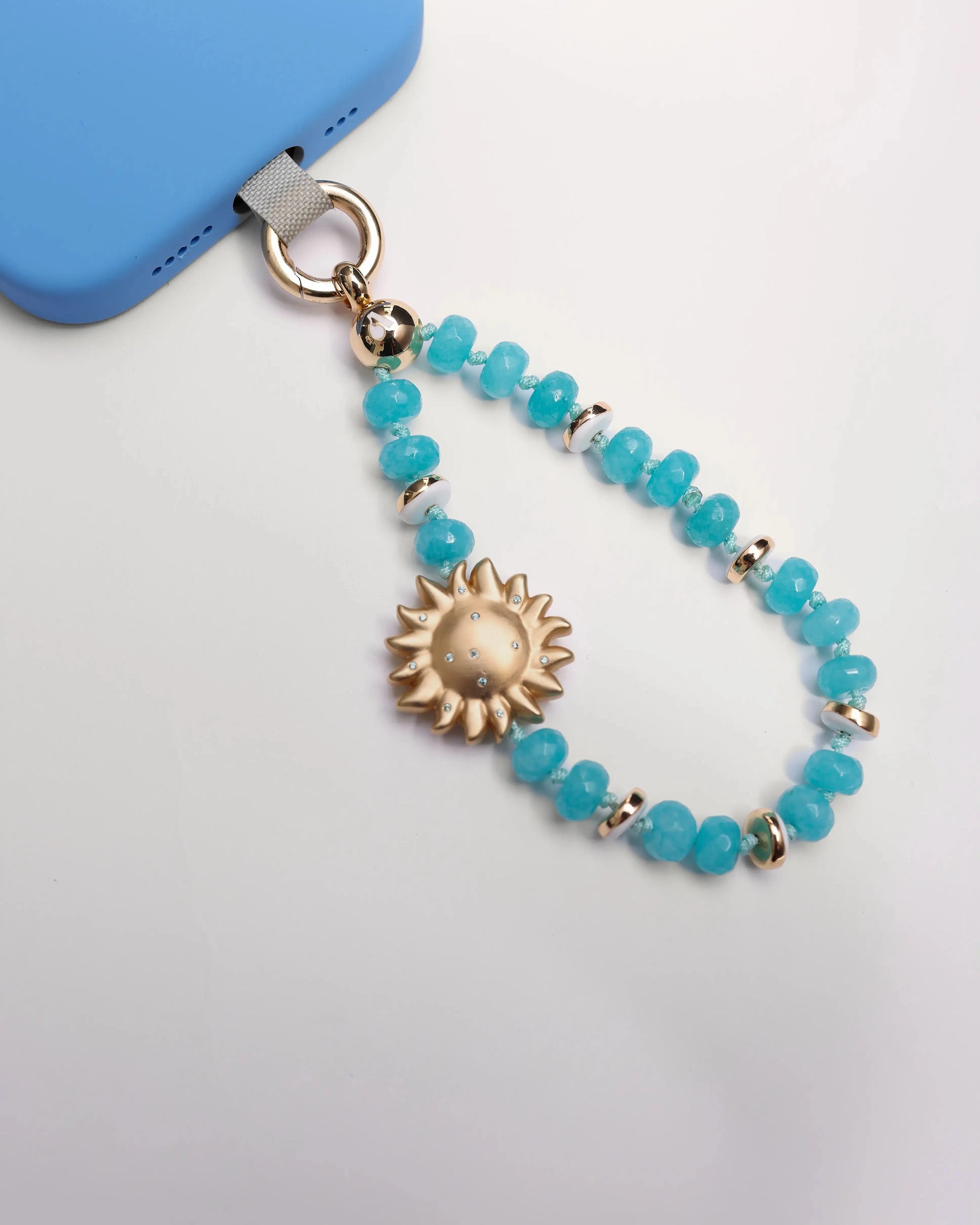 Aqua Mini India Phone Charm with Evil Eye Sun Charm styled on blue phone case.