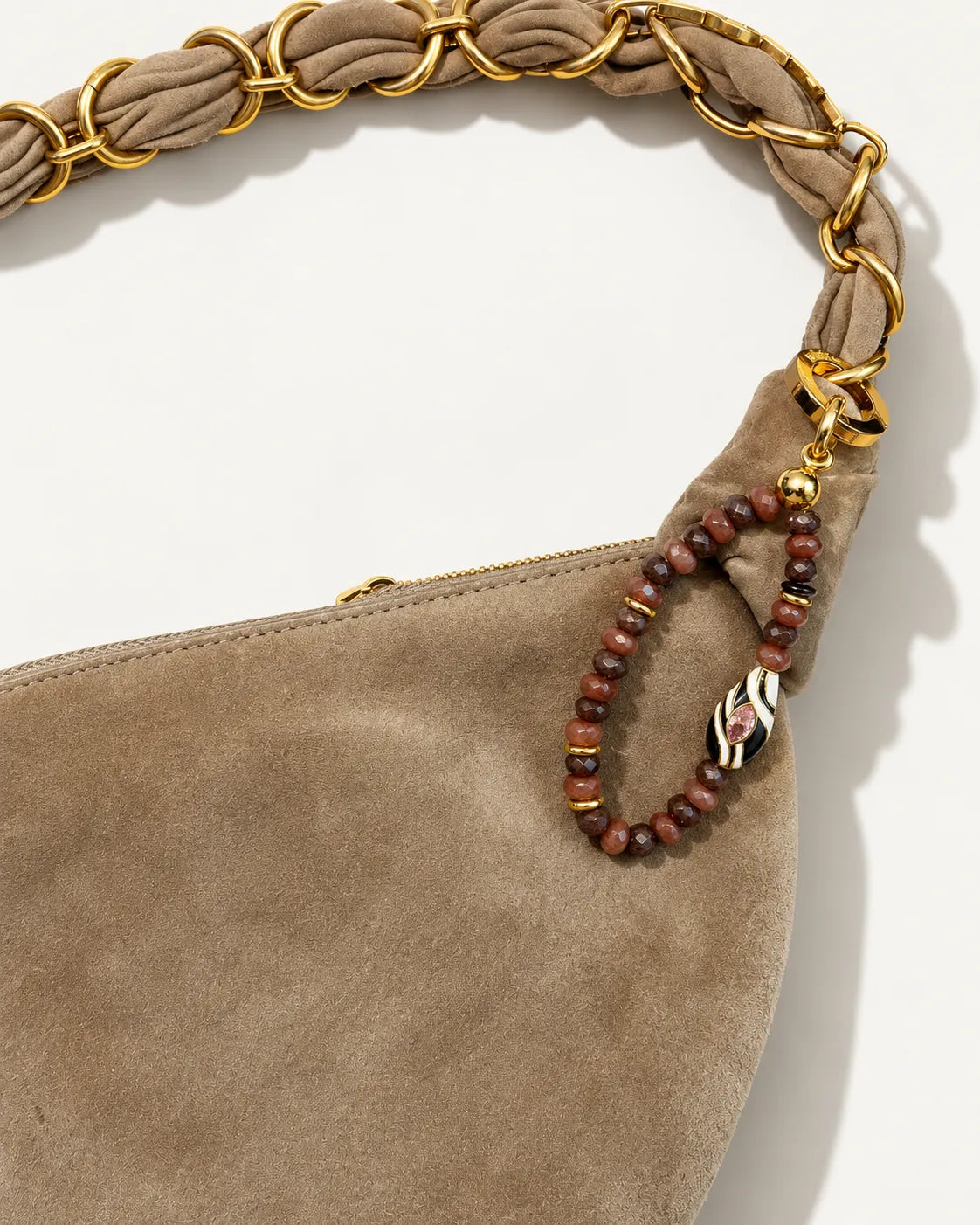 Espresso Mini Minou Bag Charm hanging from a taupe suede handbag with a gold chain strap, showcasing brown quartz beads and gold accents.