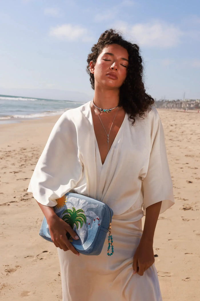 Model wearing MyAleph Large Pampelonne Denim Pouch with mini turquoise phone charm, Terre Choker Necklace, and Mayra Body Chain in a summer beach look