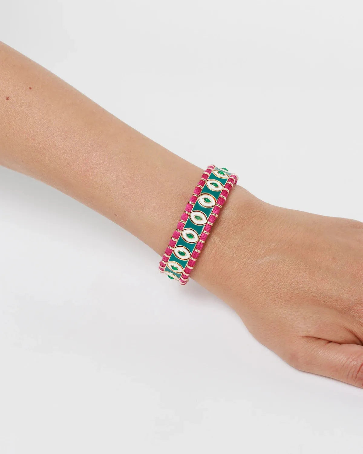 MyAleph Riviera Bracelet on wrist with green and fuchsia cotton cord, glossy enamel evil eye details, and adjustable clasp