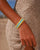 MyAleph Riviera Bracelet in Mykonos — turquoise and yellow evil eye talisman bracelet worn on wrist, styled with a cream knit summer dress at the beach.