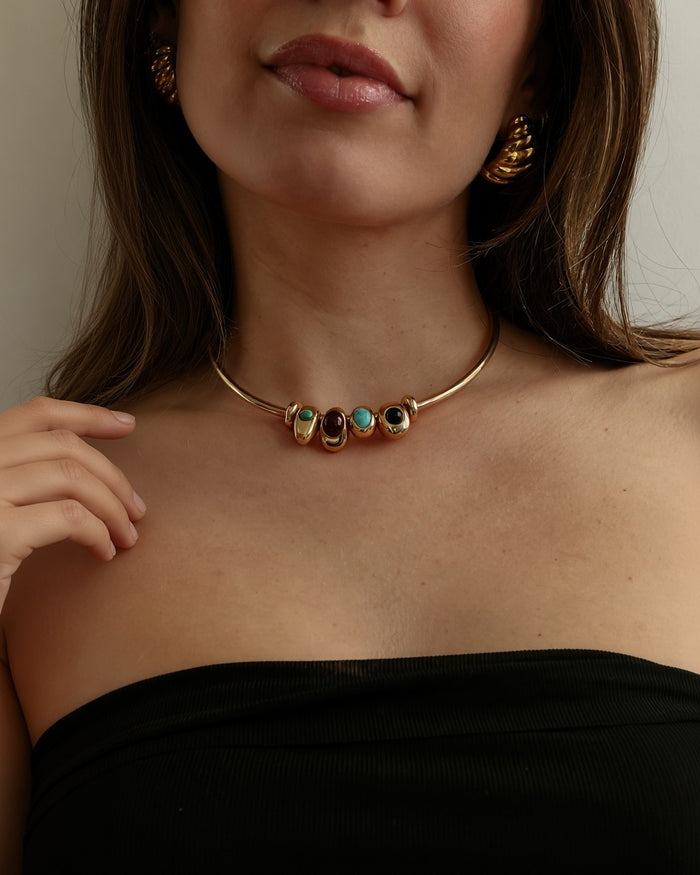 Terre gold choker necklace with turquoise, garnet and onyx charms on model in black top