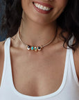 Model wearing the gold Terre Necklace with all four elemental gemstone charms at the collarbone