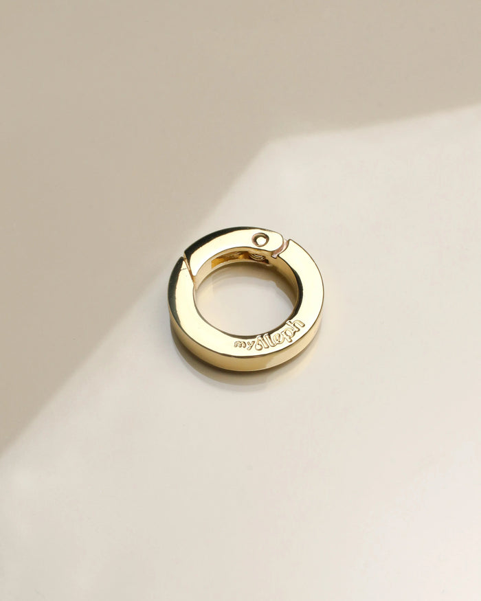 Close-up of 'The Ring' accessory in gold, displaying its sleek, polished finish with a user-friendly spring clasp, designed for versatile styling.