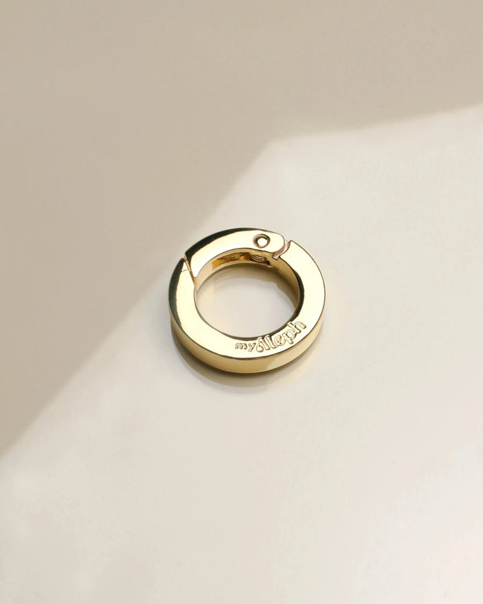 Close-up of 'The Ring' accessory in gold, displaying its sleek, polished finish with a user-friendly spring clasp, designed for versatile styling.