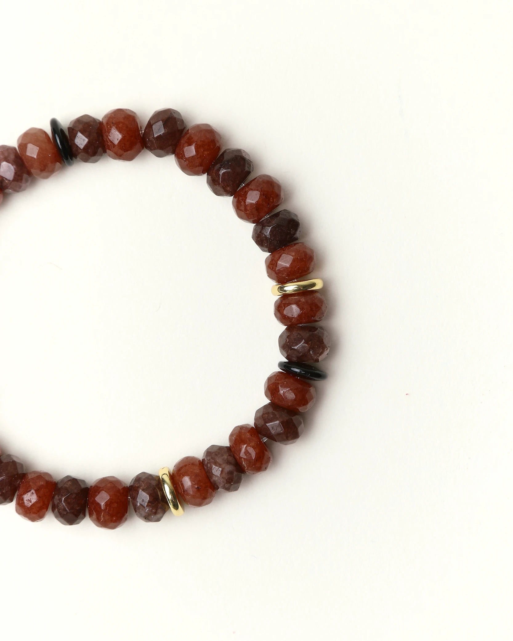 Close-up flat lay of an Espresso quartz beaded bracelet with gold spacer accents on a soft cream background