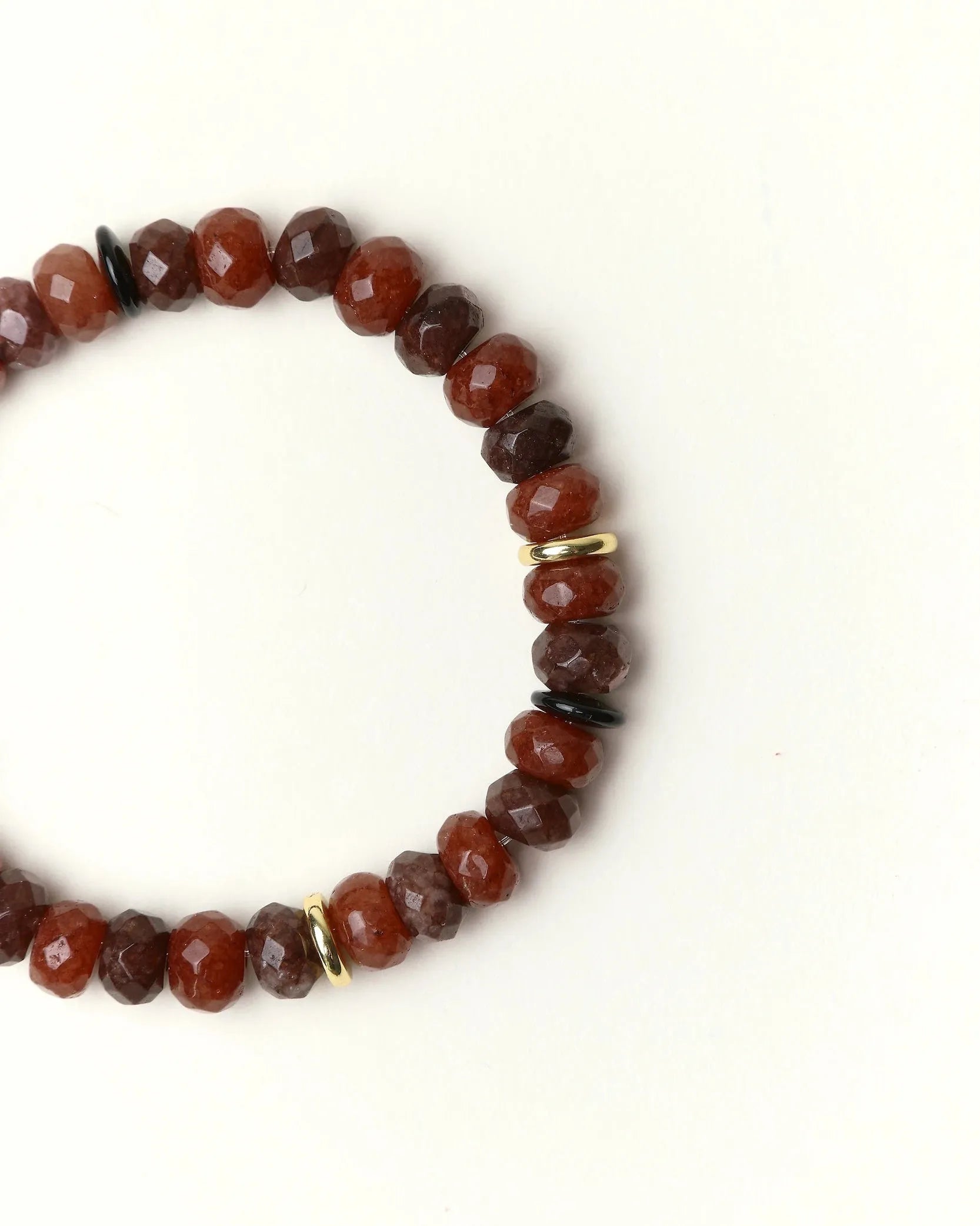 Close-up flat lay of an Espresso quartz beaded bracelet with gold spacer accents on a soft cream background