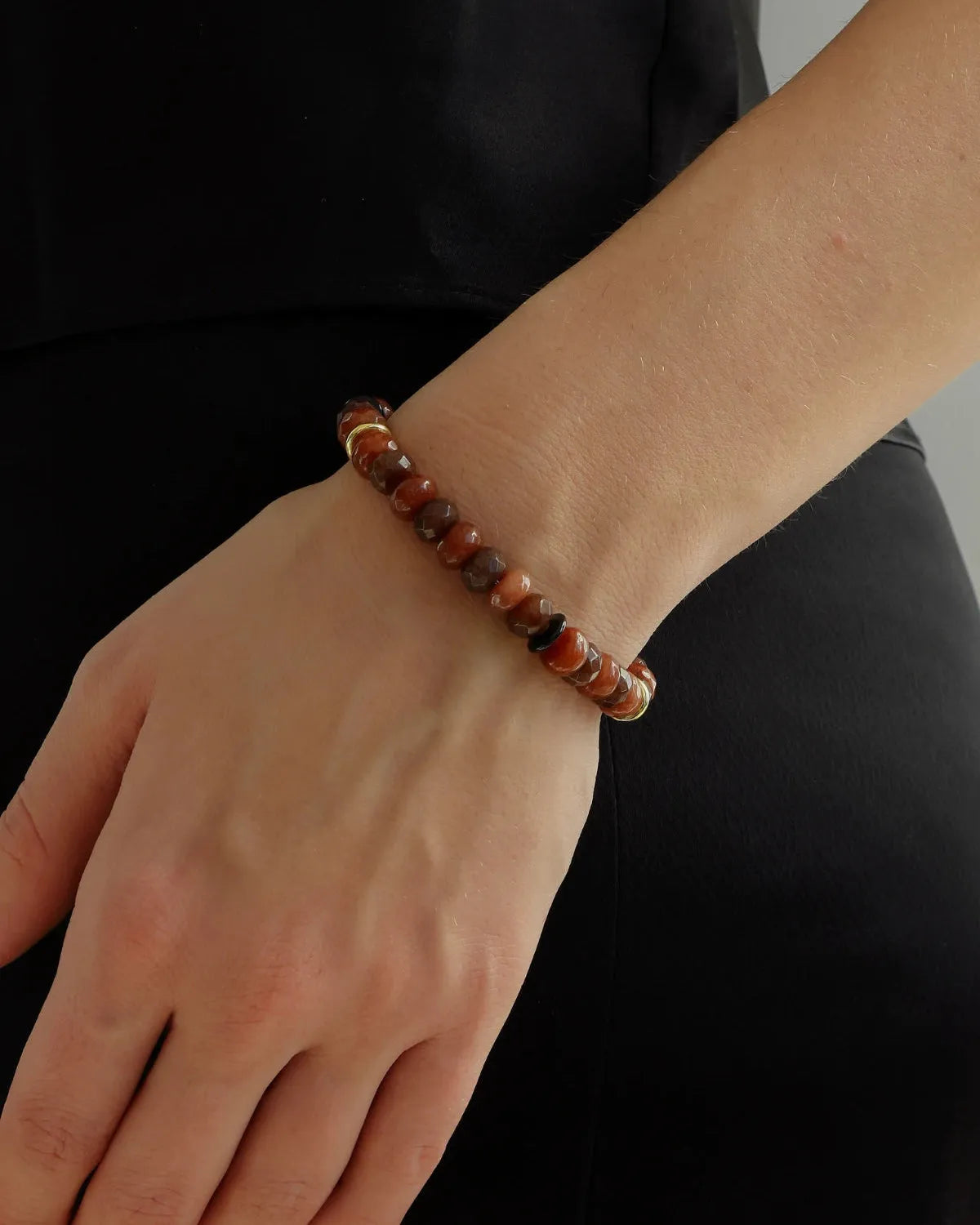 Espresso-toned quartz beaded bracelet with gold accents worn on wrist, brown gemstone bracelet styled with minimalist black outfit
