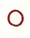 Zoe Ruby quartz beaded bracelet with gold spacer details photographed in a full flat lay on a soft cream background