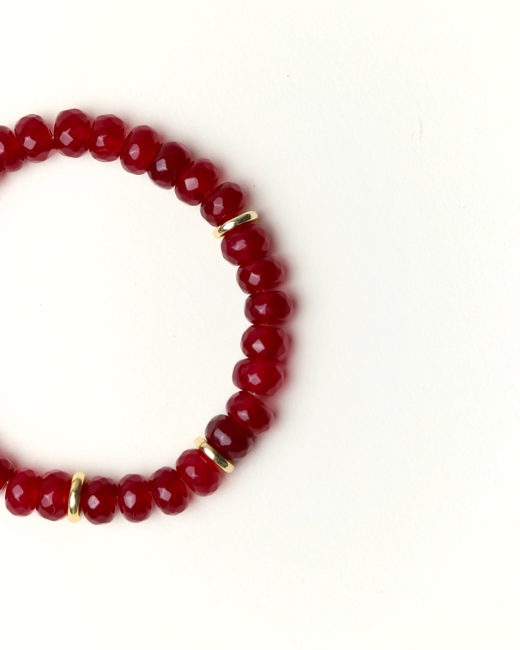 Close-up flat lay of Zoe Ruby quartz beaded bracelet with gold spacer accents on a soft cream background