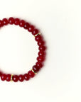 Close-up flat lay of Zoe Ruby quartz beaded bracelet with gold spacer accents on a soft cream background