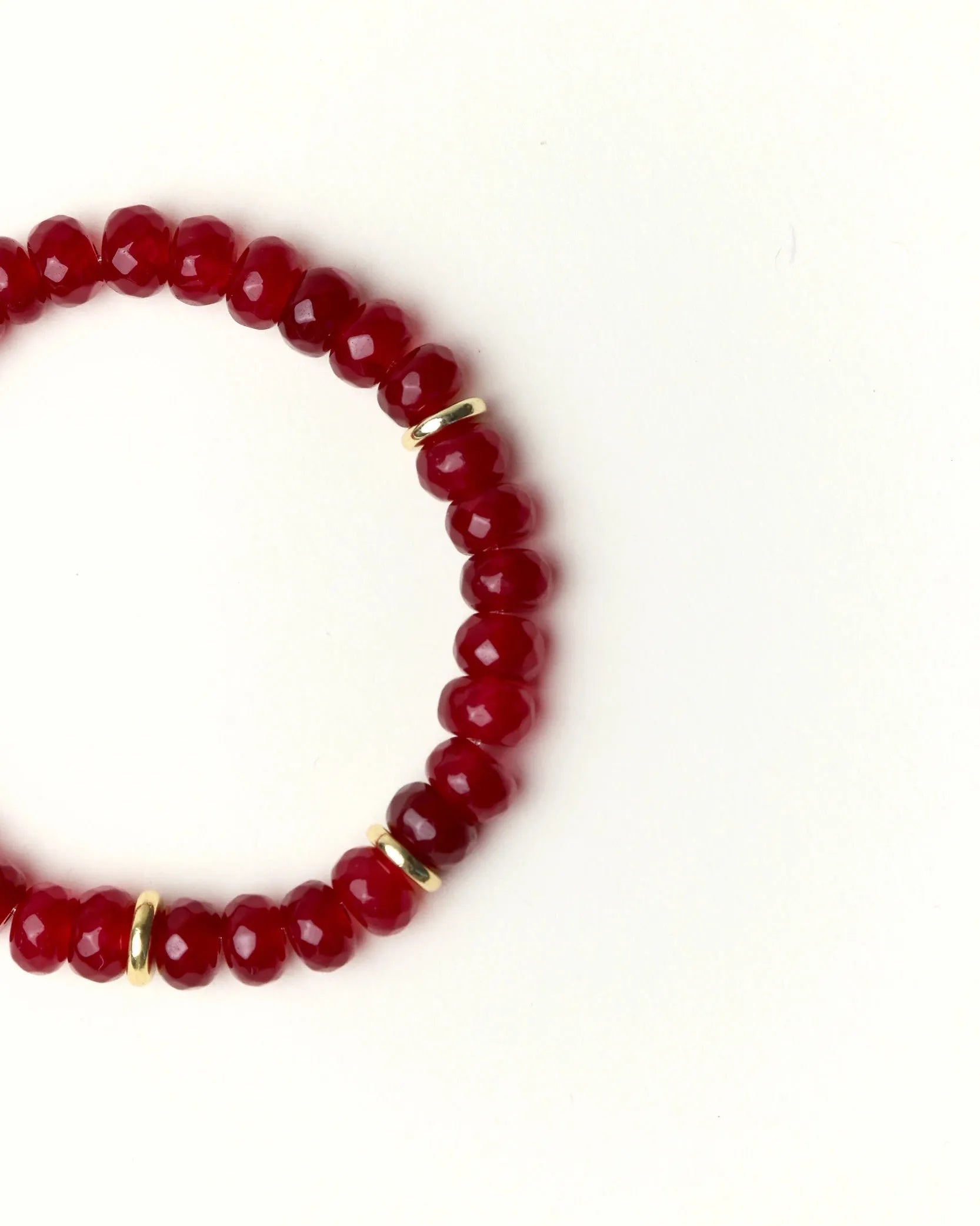 Close-up flat lay of Zoe Ruby quartz beaded bracelet with gold spacer accents on a soft cream background