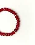 Close-up flat lay of Zoe Ruby quartz beaded bracelet with gold spacer accents on a soft cream background