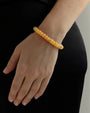 Tangerine quartz beaded bracelet with gold accents worn on wrist, vibrant orange gemstone jewelry styled with black outfit