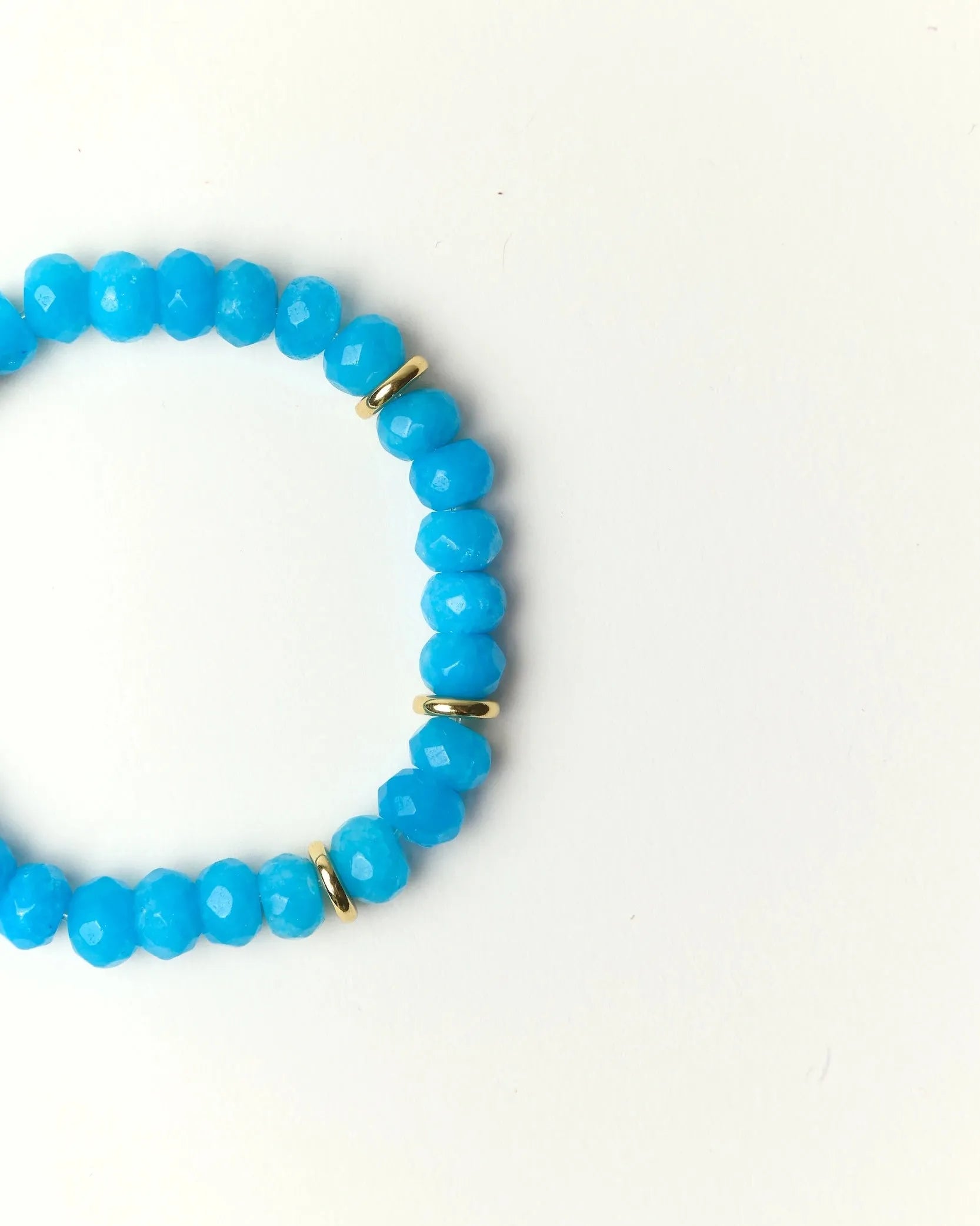 Close-up flat lay of Zoe Azure quartz beaded bracelet with gold spacer accents on a soft cream background