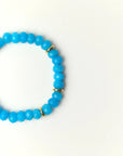 Close-up flat lay of Zoe Azure quartz beaded bracelet with gold spacer accents on a soft cream background