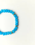 Close-up flat lay of Zoe Azure quartz beaded bracelet with gold spacer accents on a soft cream background