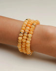 Set of three Zoe bracelets featuring vibrant tangerine quartz beads stacked on a wrist, showcasing a radiant and cheerful design.
