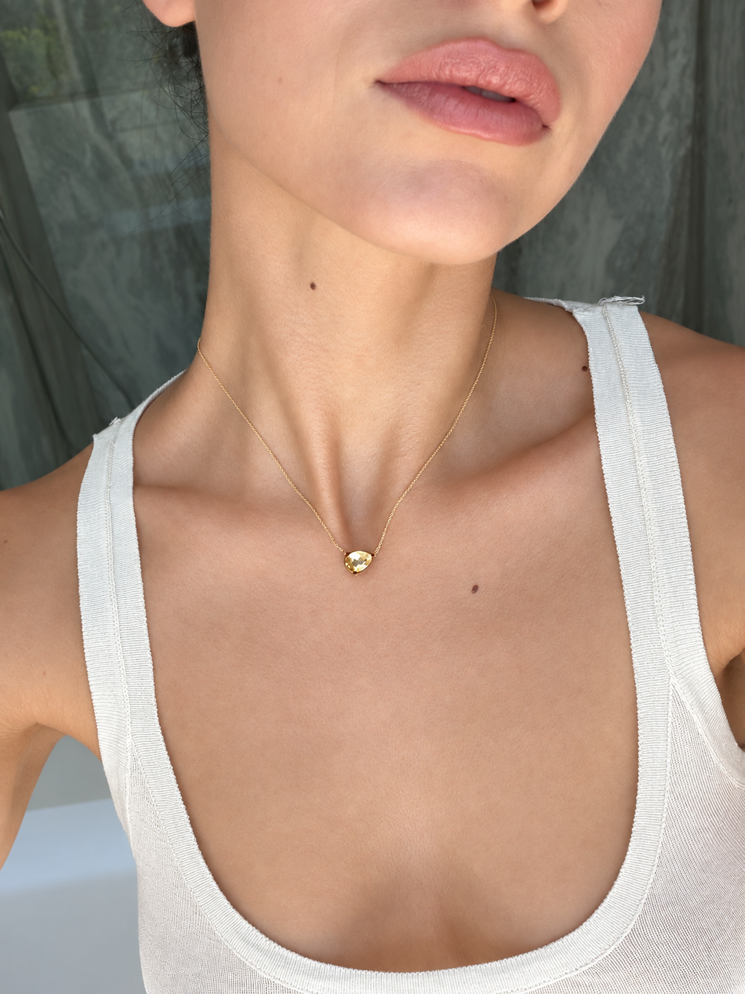 Model wearing the Eden Necklace with a Citrine Gemstone and a white tank top