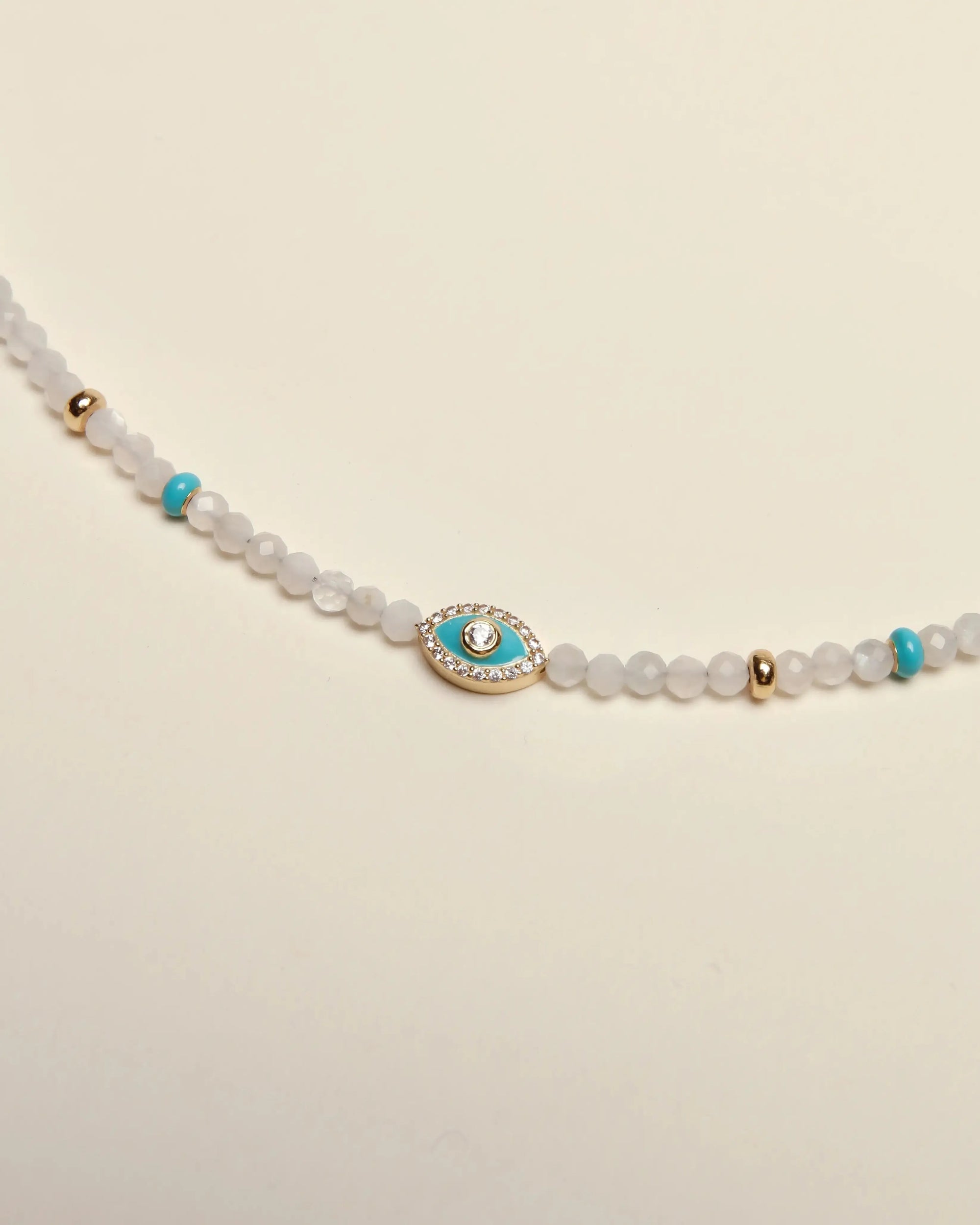 Close-up of the Juliana Necklace in Moonstone, highlighting the turquoise enamel evil eye charm and delicate gold accents.