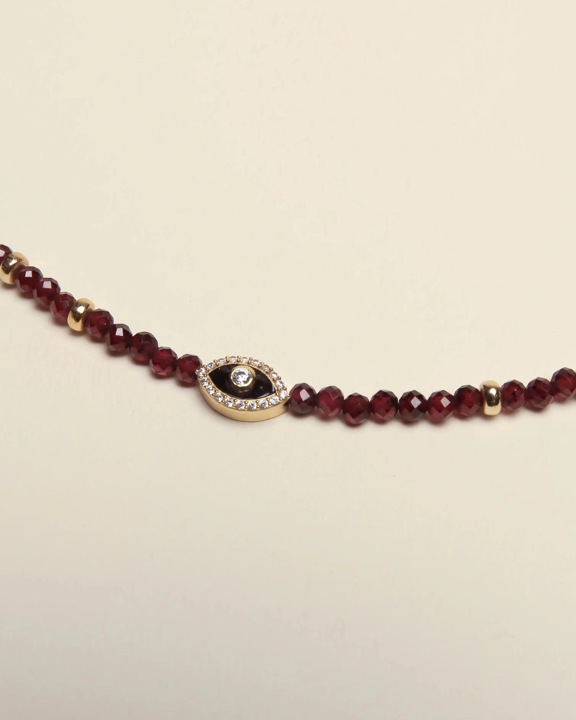 Close-up detail of the Julianna Garnet Necklace, showcasing the faceted beads and pavé evil eye charm centerpiece.