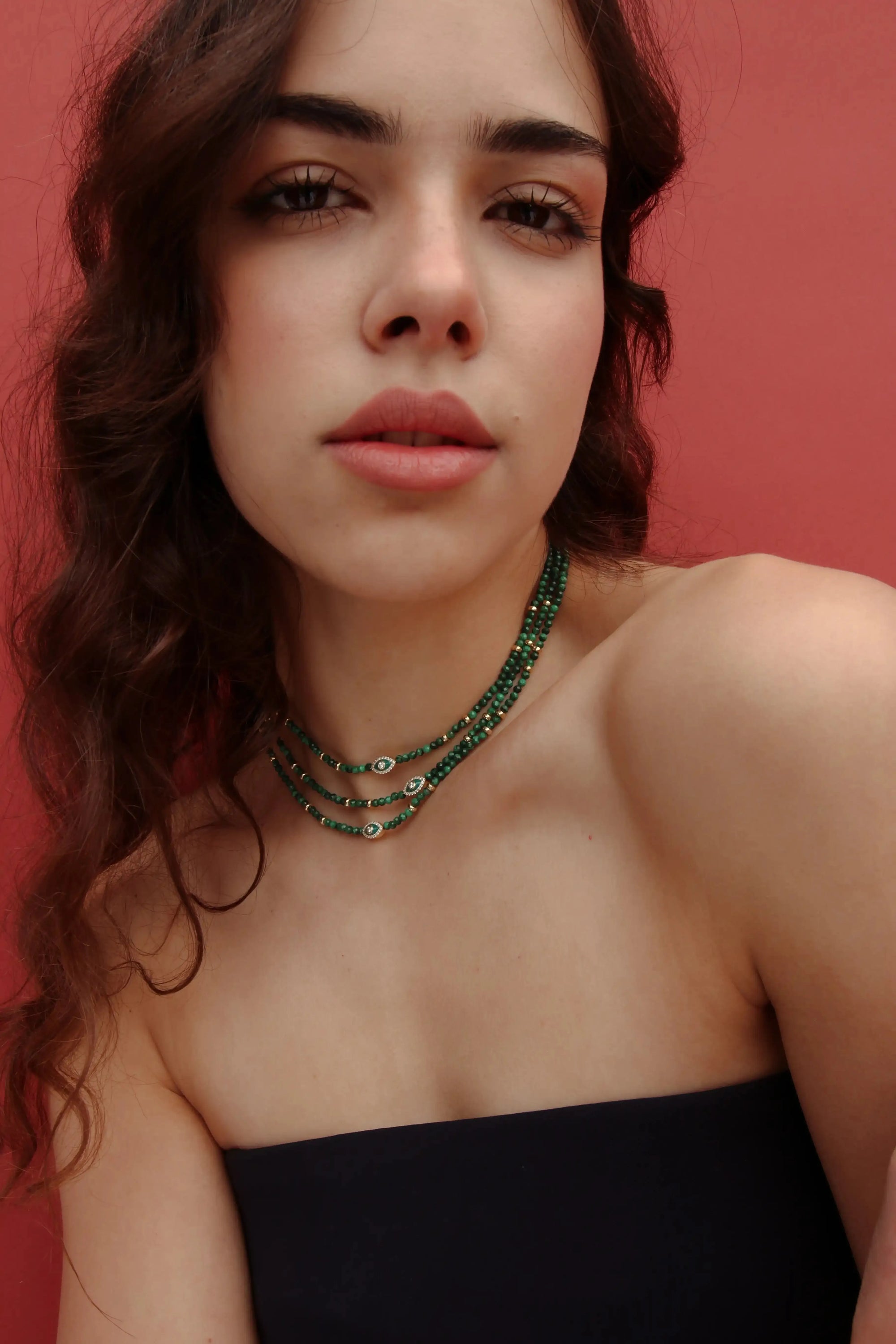 Model wearing the Julianna Necklace in Malachite with a strapless black top, highlighting the bold green beads and evil eye charm.